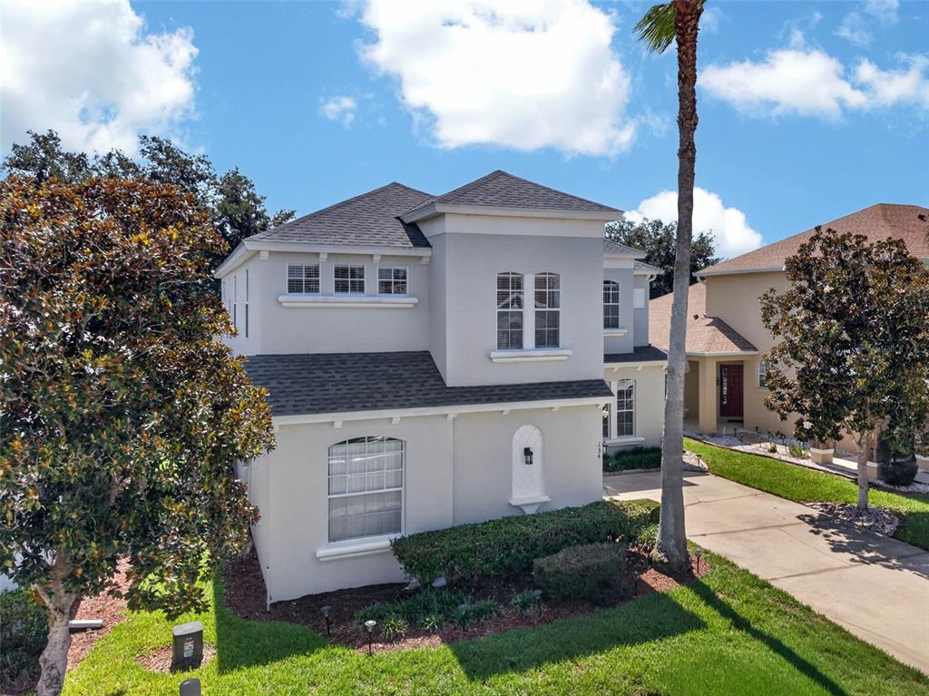 An exterior view of a two-story light gray house with a driveway and palm tree — 134 MINNIEHAHA CIRCLE, HAINES CITY, FL