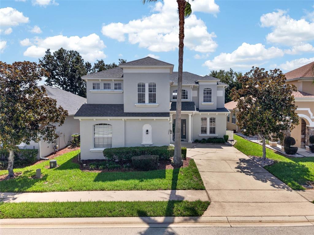 A two-story suburban house with a gray exterior, a concrete driveway, and a palm tree — 134 MINNIEHAHA CIRCLE, HAINES CITY, FL