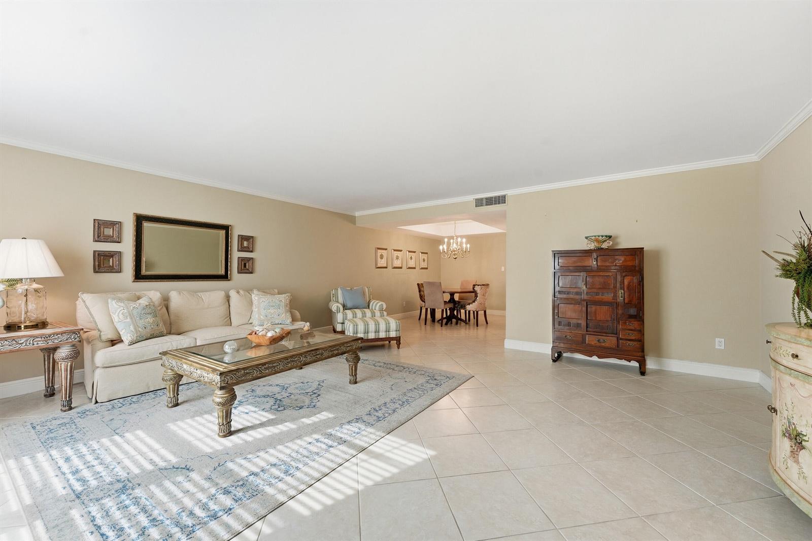 A living room with beige walls, tile flooring, a sofa, and an adjacent dining area — 2701 Ocean Drive # 1a, Vero Beach FL 32963, VERO BEACH, FL