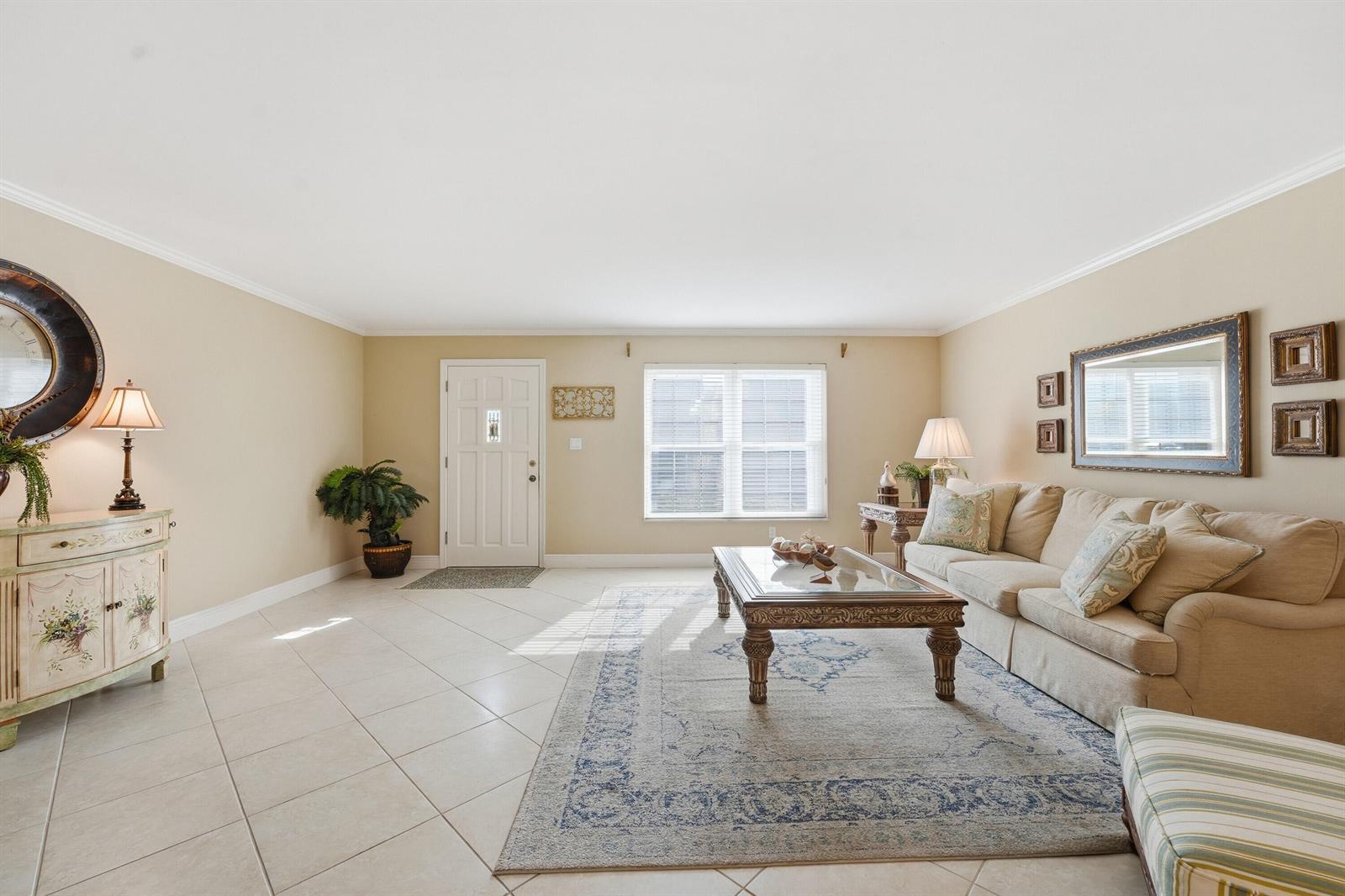 A living room features tile flooring, a beige sofa, a coffee table, and a rug — 2701 Ocean Drive # 1a, Vero Beach FL 32963, VERO BEACH, FL