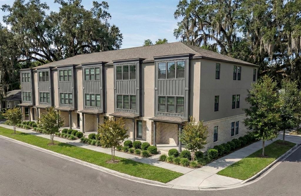 A multi-unit residential building with gray siding, brick accents, and dark-framed windows on a corner — 3208 N TAMPA STREET, TAMPA, FL