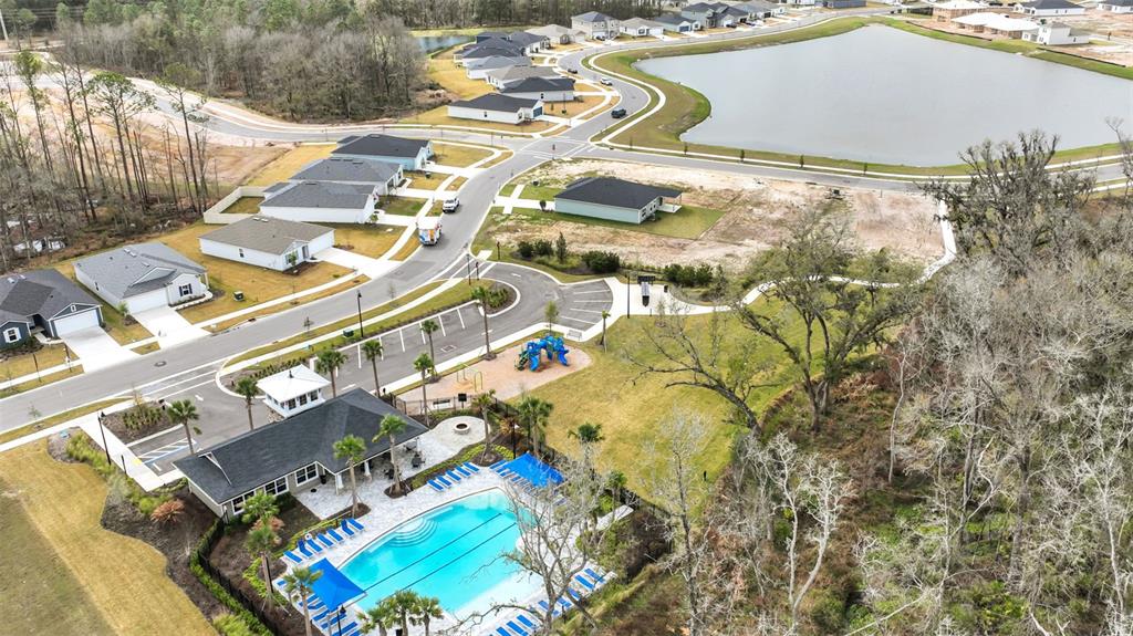 An aerial view shows a community pool, clubhouse, playground, and surrounding suburban houses near a lake — 3167 GADWALL ROAD, ORANGE PARK, FL