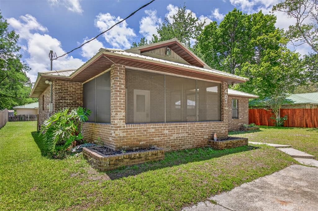 A brick house features a large screened-in front porch and a metal roof — 407 POMONT AVENUE, ST AUGUSTINE, FL