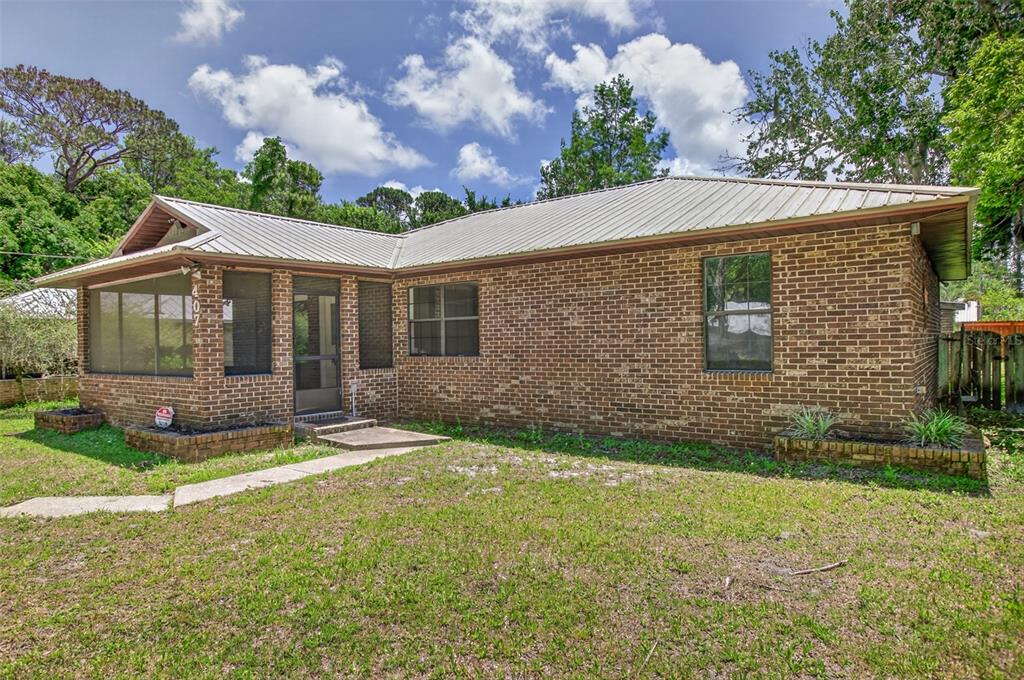 A single-story brick house with a metal roof and a screened-in front porch — 407 POMONT AVENUE, ST AUGUSTINE, FL