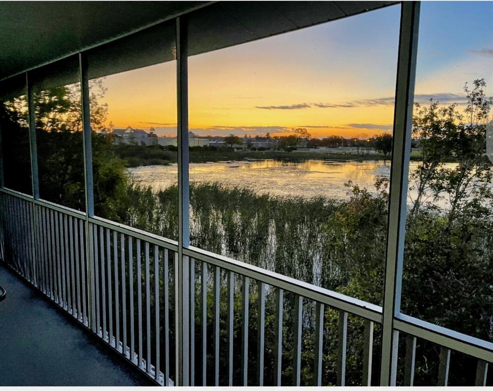 A screened-in balcony overlooks a lake with tall reeds at sunset — 3143 SUN LAKE COURT UNIT B, KISSIMMEE, FL