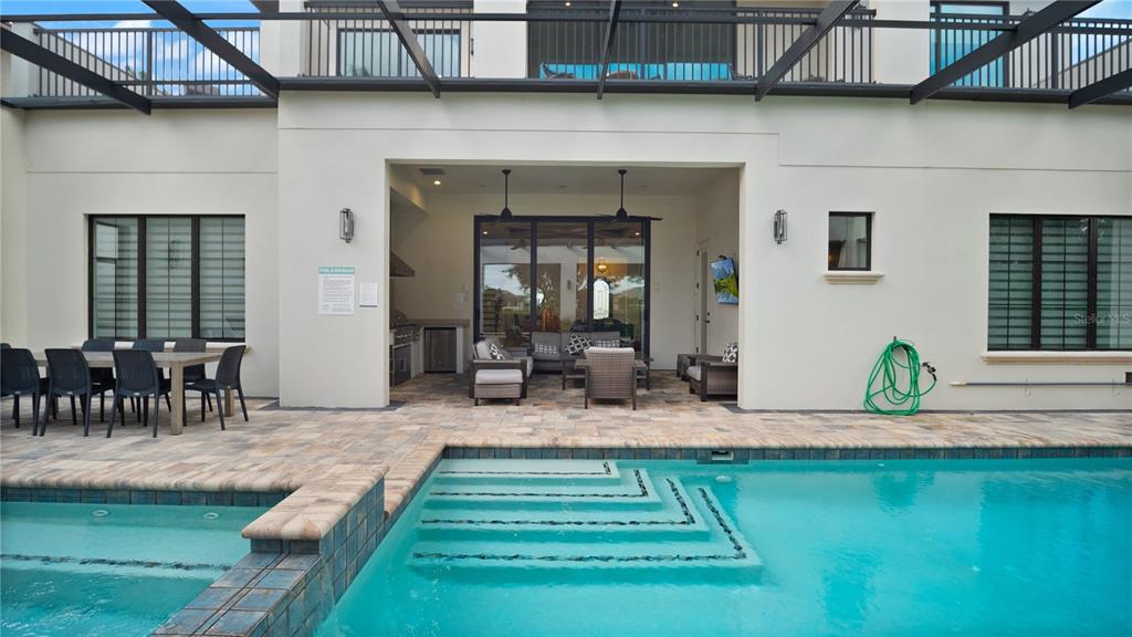 A covered patio with outdoor furniture and a kitchen overlooks a swimming pool and spa — 1253 RADIANT STREET, REUNION, FL
