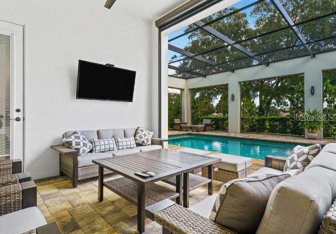 A covered outdoor patio features a television, wicker seating, and a swimming pool — 1253 RADIANT STREET, REUNION, FL