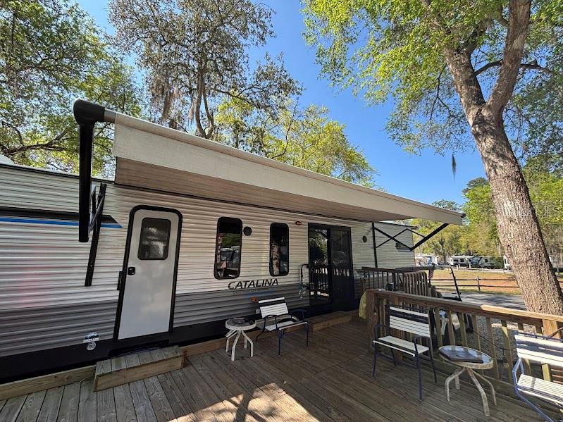 A Catalina travel trailer with an extended awning sits on a wooden deck outdoors — 14403 252ND COURT ROAD NE UNIT 128, FORT MC COY, FL