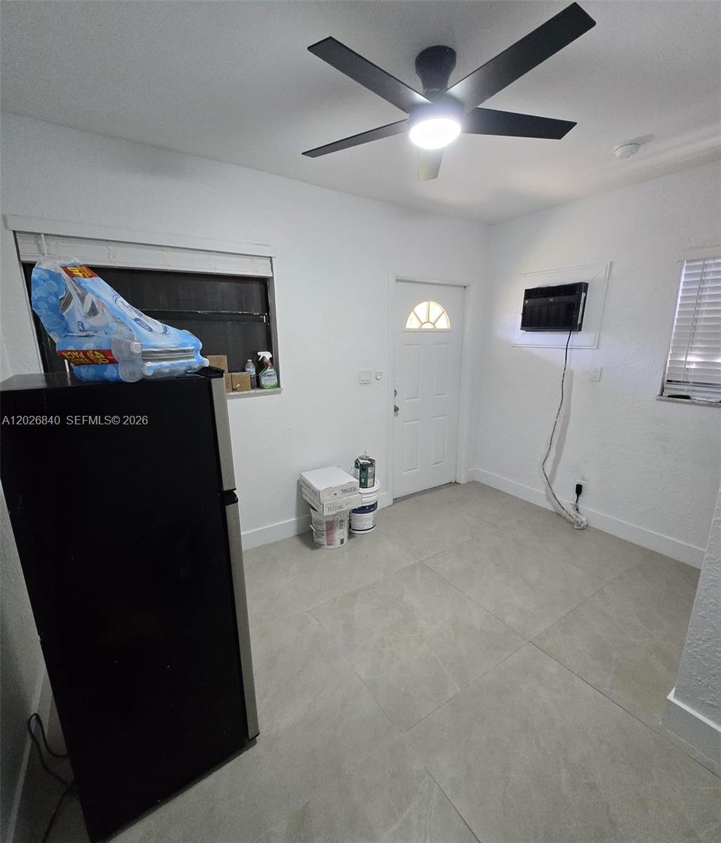 A kitchen area features a black refrigerator, tiled floors, a ceiling fan, and a wall-mounted AC — 4130 SW 19th St # 3, West Park FL 33023, WEST PARK, FL