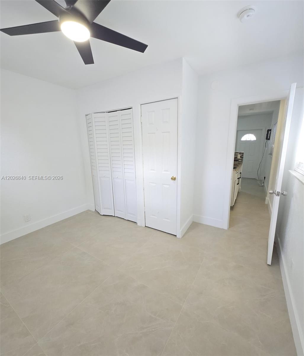 A bedroom with light tile flooring, a ceiling fan, and two white closet doors — 4130 SW 19th St # 3, West Park FL 33023, WEST PARK, FL