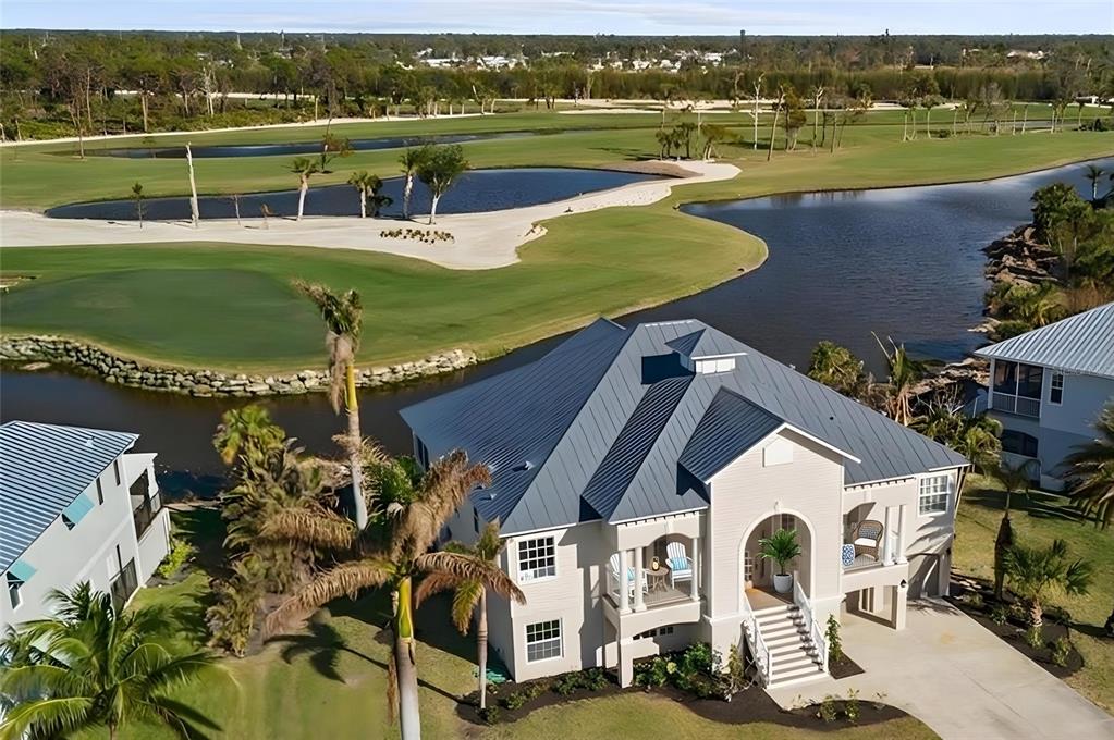 An aerial view of a two-story house with a metal roof overlooking a golf course — 10030 EAGLE PRESERVE DRIVE, ENGLEWOOD, FL