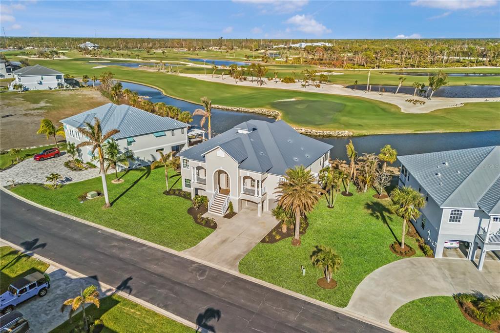 An aerial view shows three houses situated along a golf course and a winding canal — 10030 EAGLE PRESERVE DRIVE, ENGLEWOOD, FL