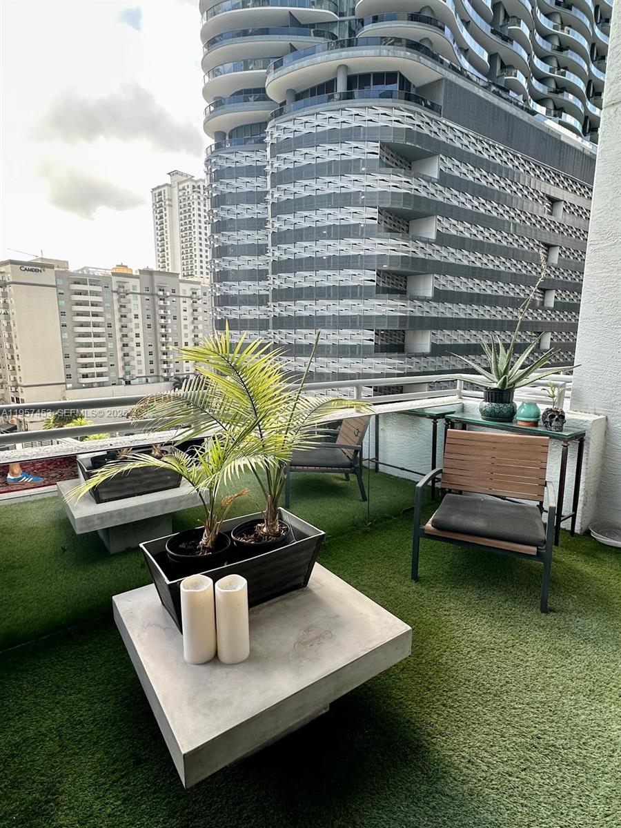 A balcony with artificial turf, patio furniture, and potted plants overlooks a city skyline — 1050 Brickell Ave # 818, Miami FL 33131, MIAMI, FL