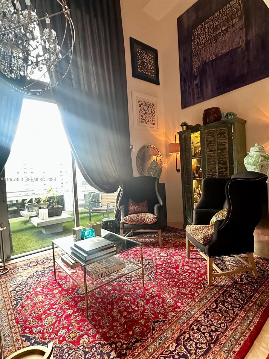 A living room features two black wingback chairs, a red patterned rug, and a balcony — 1050 Brickell Ave # 818, Miami FL 33131, MIAMI, FL