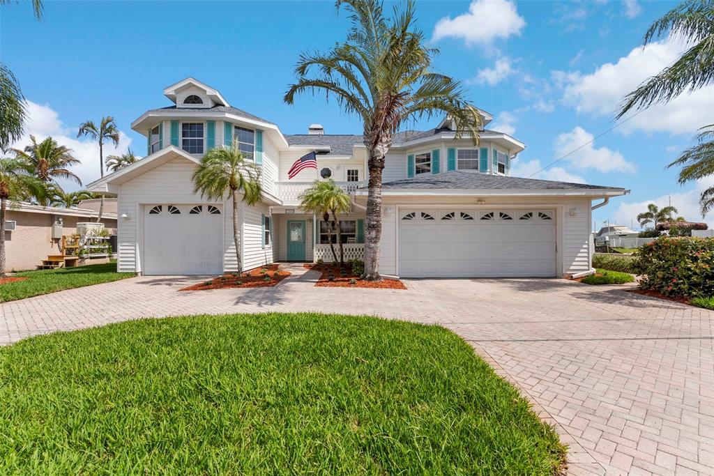 A two-story white house with a multi-car garage and a paved driveway — 11445 9TH STREET E, TREASURE ISLAND, FL