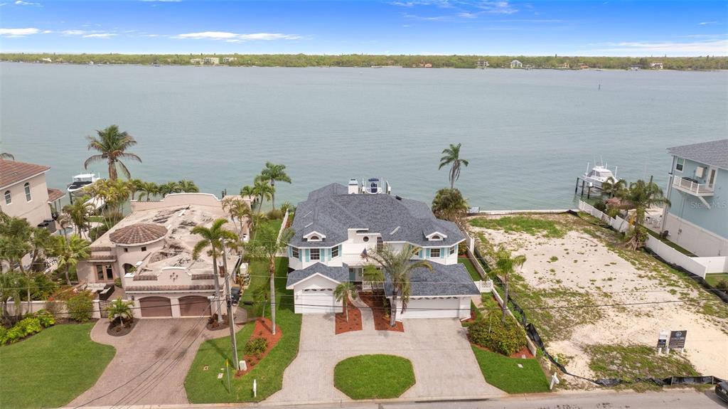 An aerial view shows a two-story house with a dark roof situated between two properties — 11445 9TH STREET E, TREASURE ISLAND, FL