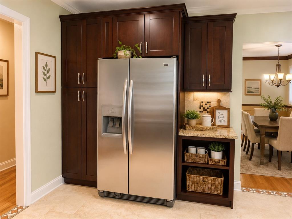 A stainless steel refrigerator is flanked by dark wood cabinetry and an open shelving unit — 1029 W COUNTRY CLUB CIRCLE, PLANTATION, FL