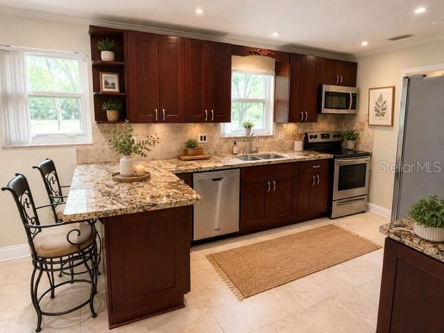 A kitchen features dark wood cabinets, granite countertops, stainless steel appliances, and a breakfast bar — 1029 W COUNTRY CLUB CIRCLE, PLANTATION, FL