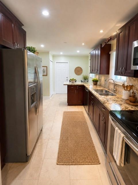 A kitchen features dark wood cabinets, stainless steel appliances, granite countertops, and light tile flooring — 1029 W COUNTRY CLUB CIRCLE, PLANTATION, FL