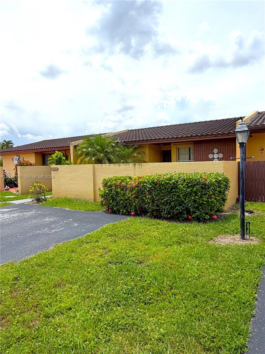 A single-story residential building features a stucco exterior, a tiled roof, and a front hedge — 14725 SW 86th Ln, Miami FL 33193, MIAMI, FL