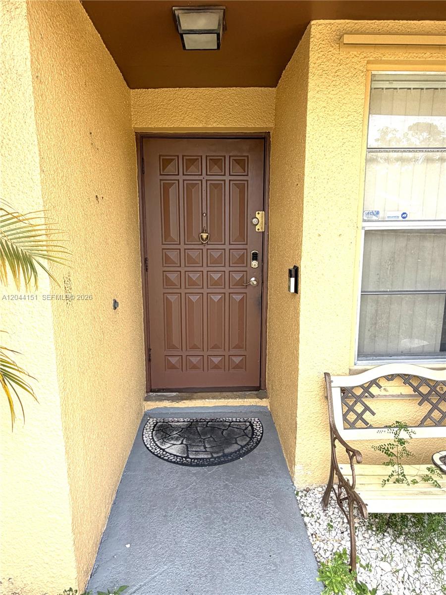 A brown front door with a knocker is set in a yellow stucco entryway — 14725 SW 86th Ln, Miami FL 33193, MIAMI, FL