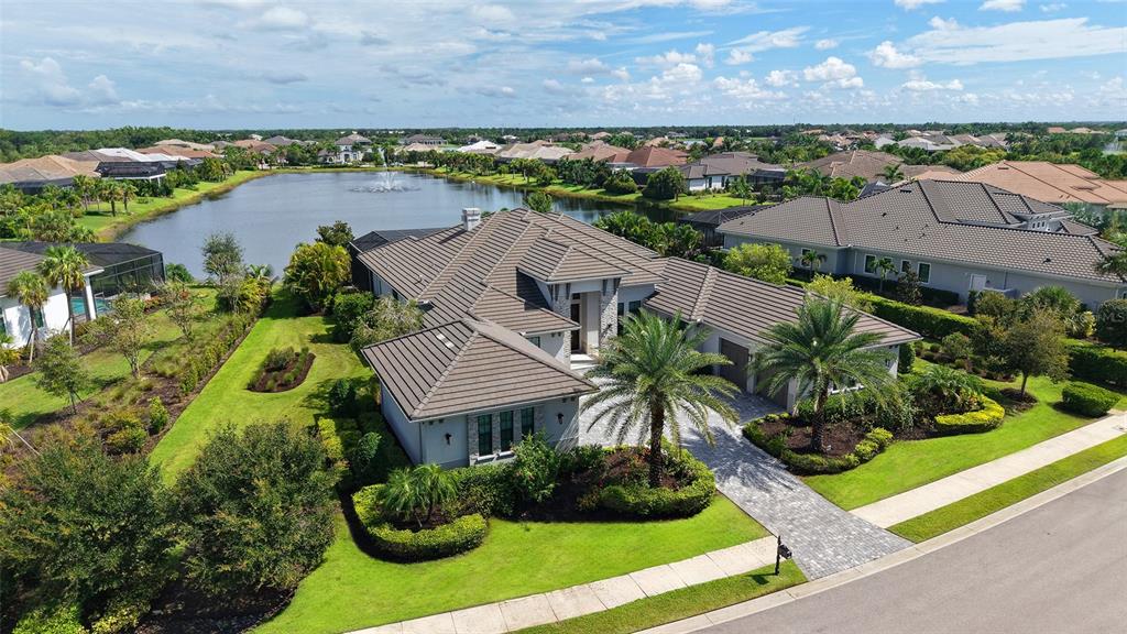 An aerial view of a single-story house with a tiled roof next to a lake — 8339 LUCERNE LOOP, BRADENTON, FL