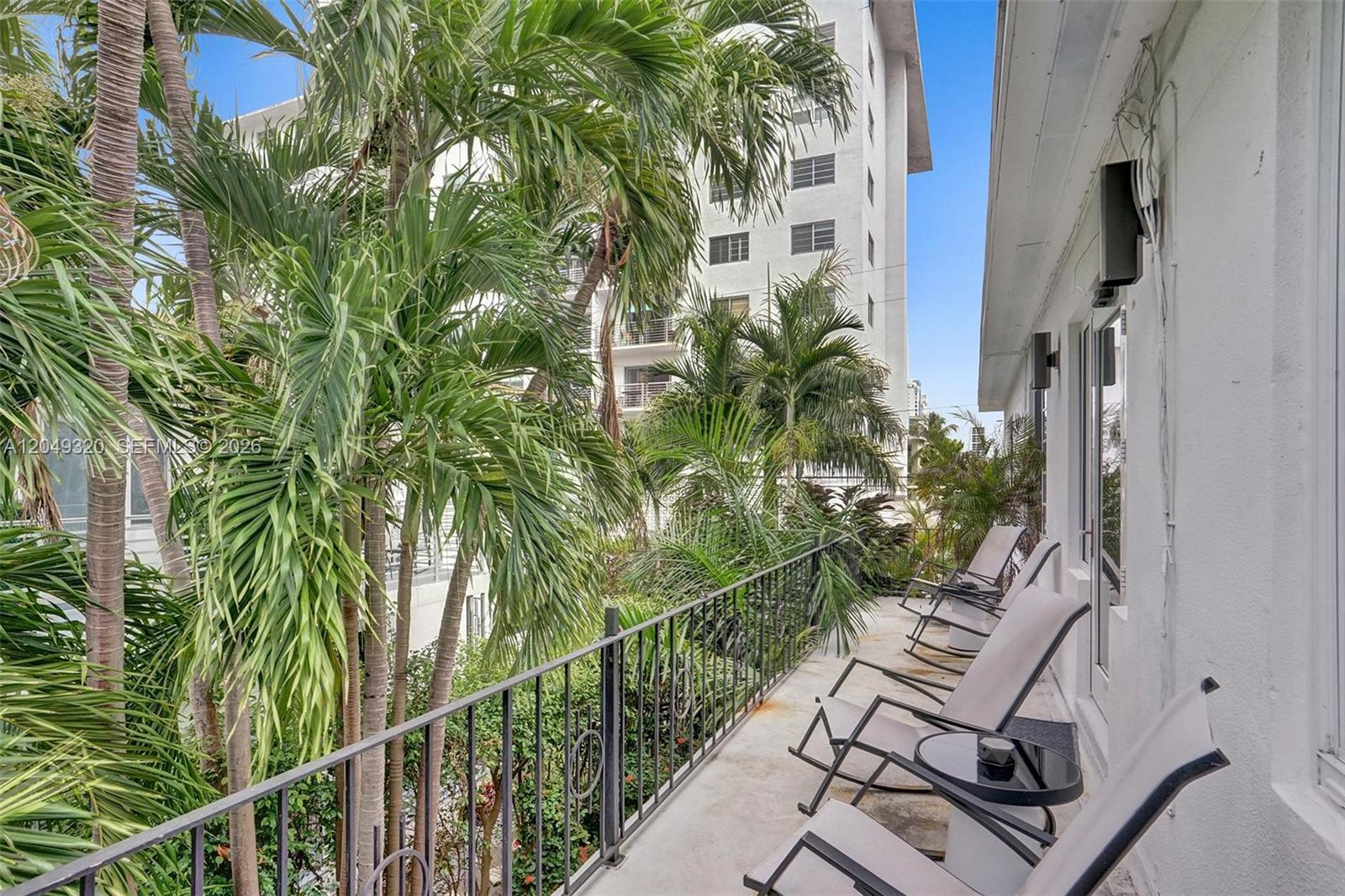 A balcony with a metal railing, several outdoor chairs, and views of palm trees — 1431 Lincoln Ter # 3, Miami Beach FL 33139, MIAMI BEACH, FL