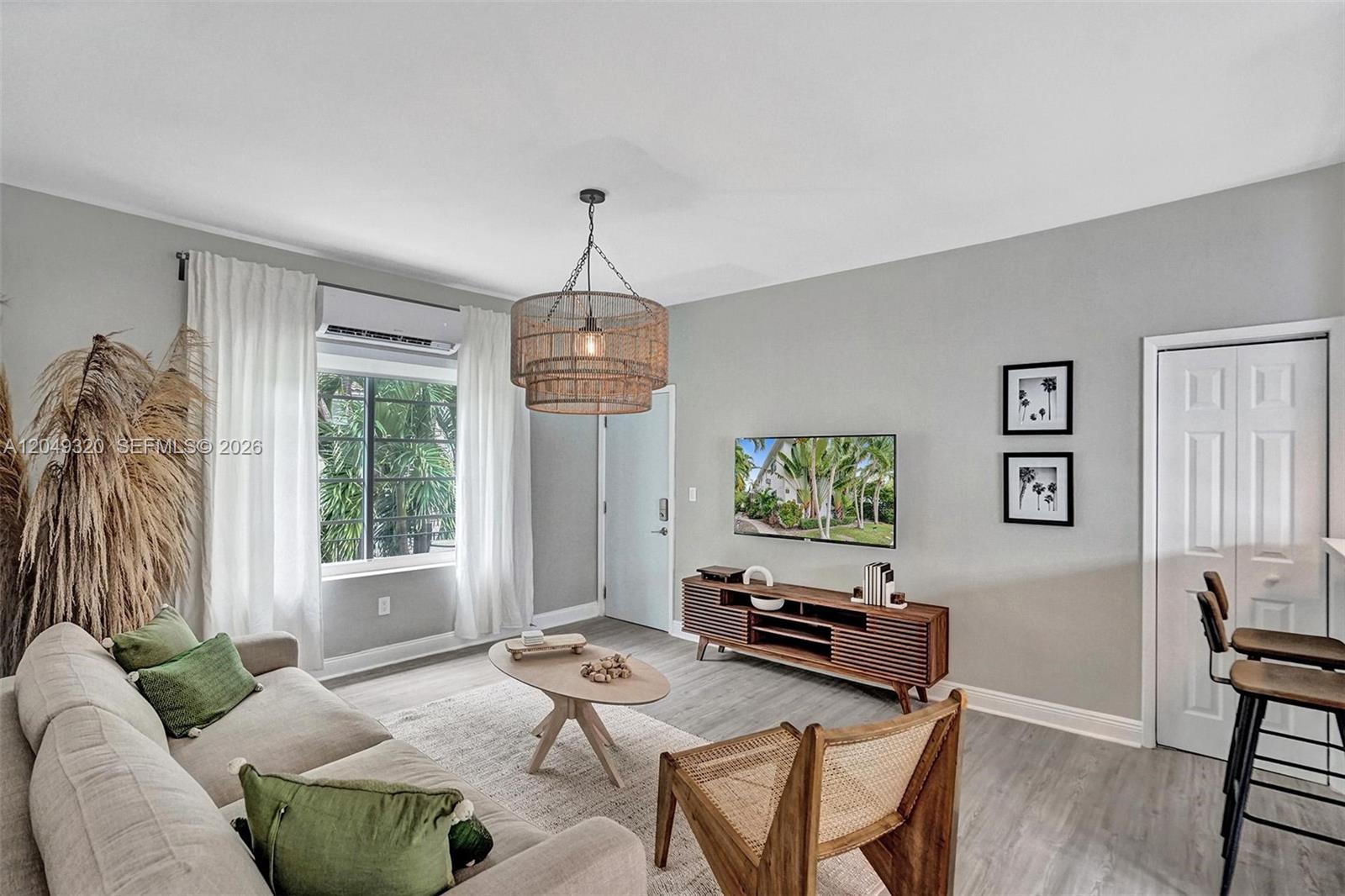 A living room features a sofa, coffee table, TV, and a woven pendant light — 1431 Lincoln Ter # 3, Miami Beach FL 33139, MIAMI BEACH, FL