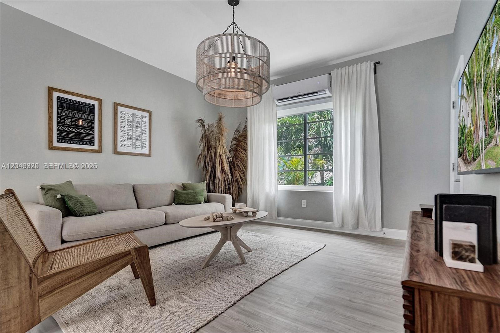 A living room features a beige sofa, a wooden chair, and a large drum chandelier — 1431 Lincoln Ter # 3, Miami Beach FL 33139, MIAMI BEACH, FL