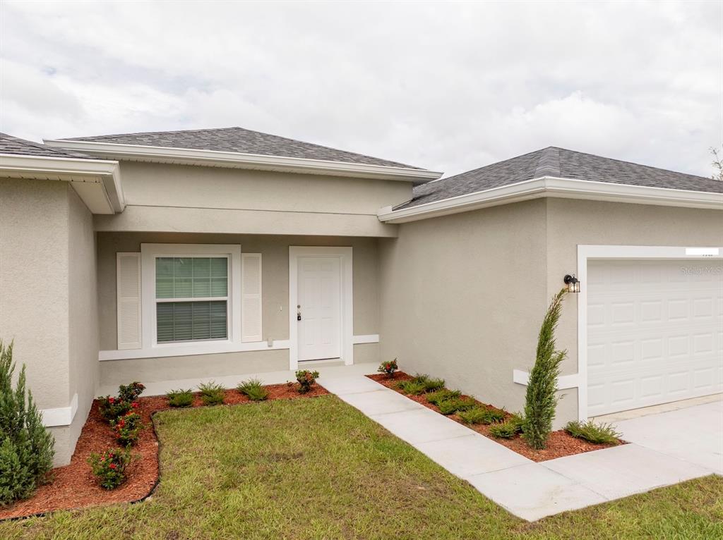 A single-story house exterior features a white front door, a garage, and a landscaped yard — 7764 N DARBY DRIVE, CITRUS SPRINGS, FL