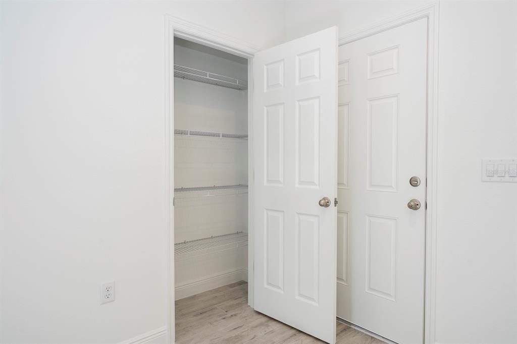 A white room features an open closet with wire shelving and a closed door — 7764 N DARBY DRIVE, CITRUS SPRINGS, FL