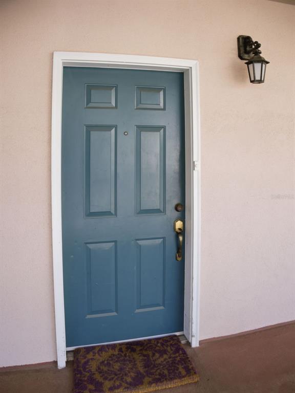 A blue front door with a brass handle and a doormat on a porch — 201 SE 2ND AVENUE UNIT 412, GAINESVILLE, FL