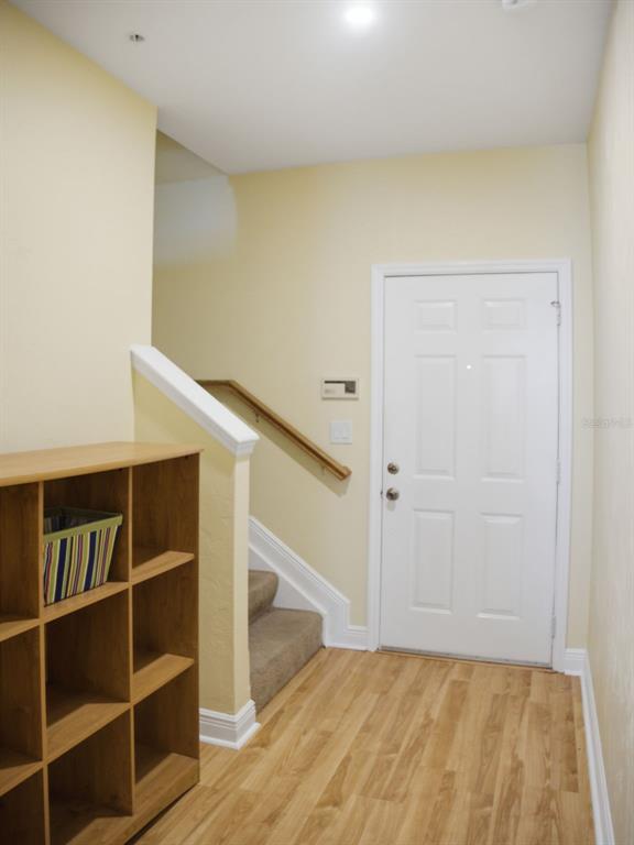 An entryway features light-colored walls, wood-look flooring, a white door, and a wooden storage unit — 201 SE 2ND AVENUE UNIT 412, GAINESVILLE, FL