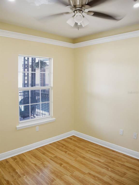 An empty room with light yellow walls, wood-look flooring, a ceiling fan, and a window — 201 SE 2ND AVENUE UNIT 412, GAINESVILLE, FL