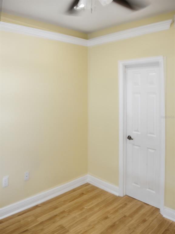 A room with light yellow walls, white crown molding, wood-look flooring, and a white door — 201 SE 2ND AVENUE UNIT 412, GAINESVILLE, FL
