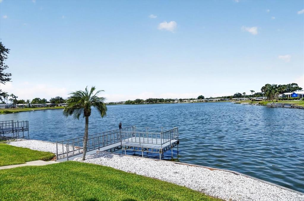 A metal dock extends into a lake from a grassy yard with a palm tree — 8469 IMPERIAL LAKES CIRCLE, PALMETTO, FL