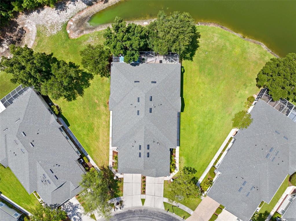 An aerial view shows three houses with gray roofs, driveways, and backyards bordering a pond — 3348 CHAPEL CREEK CIRCLE, WESLEY CHAPEL, FL