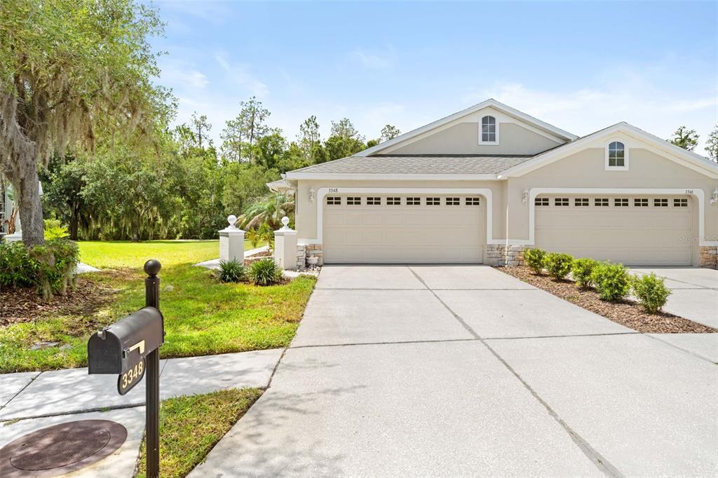 A beige duplex house with two garage doors and a mailbox in the foreground — 3348 CHAPEL CREEK CIRCLE, WESLEY CHAPEL, FL