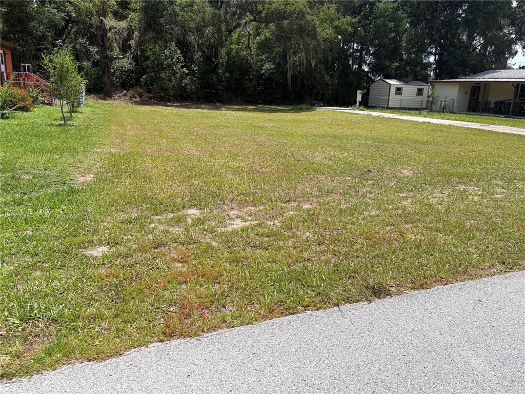 A vacant, grassy residential lot sits next to a house and a small shed — 11047 SE 66TH TERRACE, BELLEVIEW, FL
