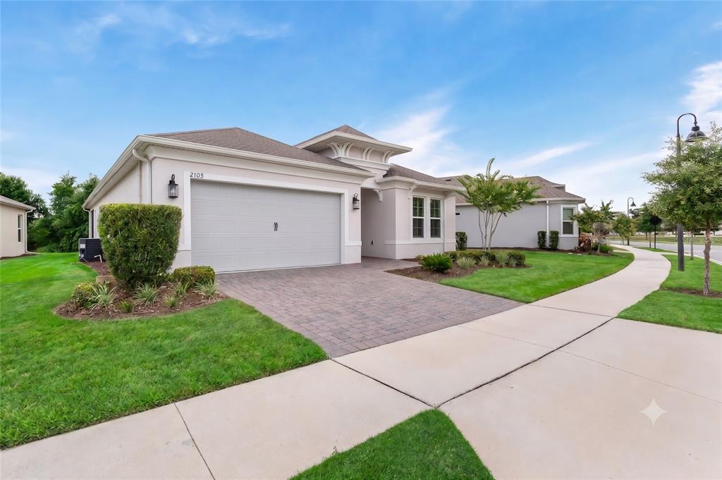 A single-story house with a beige stucco exterior, a two-car garage, and a paved driveway — 2103 LIMESTONE TRAIL, KISSIMMEE, FL