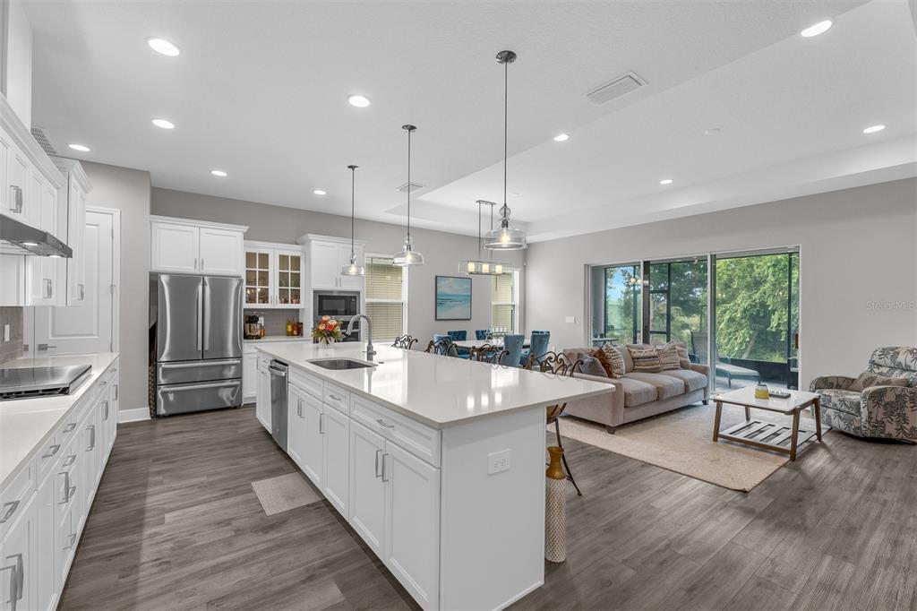 A modern open-concept kitchen with white cabinets, a large island, and an adjacent living area — 2103 LIMESTONE TRAIL, KISSIMMEE, FL