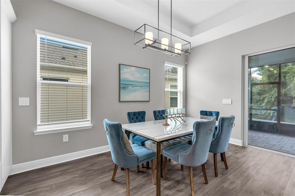 A dining room features a marble table, blue upholstered chairs, and a rectangular pendant light — 2103 LIMESTONE TRAIL, KISSIMMEE, FL