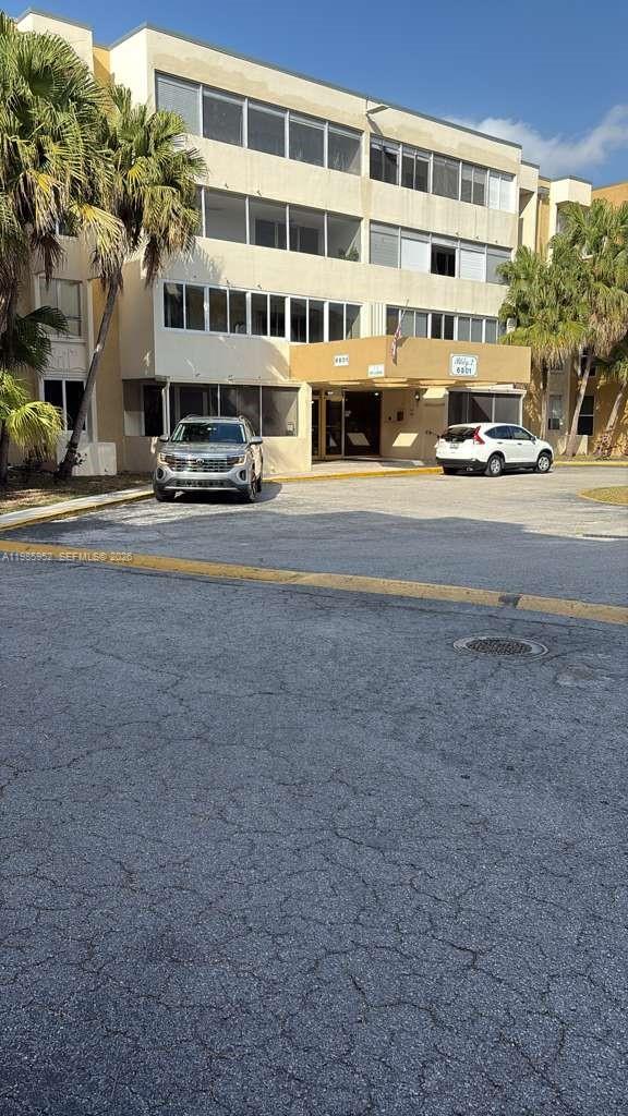A multi-story beige apartment building features a covered entrance with two parked cars — 6901 SW 147th Ave # 2E, Miami FL 33193, MIAMI, FL