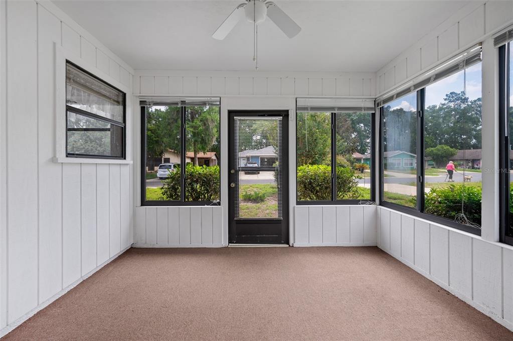A sunroom with white vertical paneling, brown carpeting, a ceiling fan, and large windows — 8496 NW 37TH TERRACE, GAINESVILLE, FL