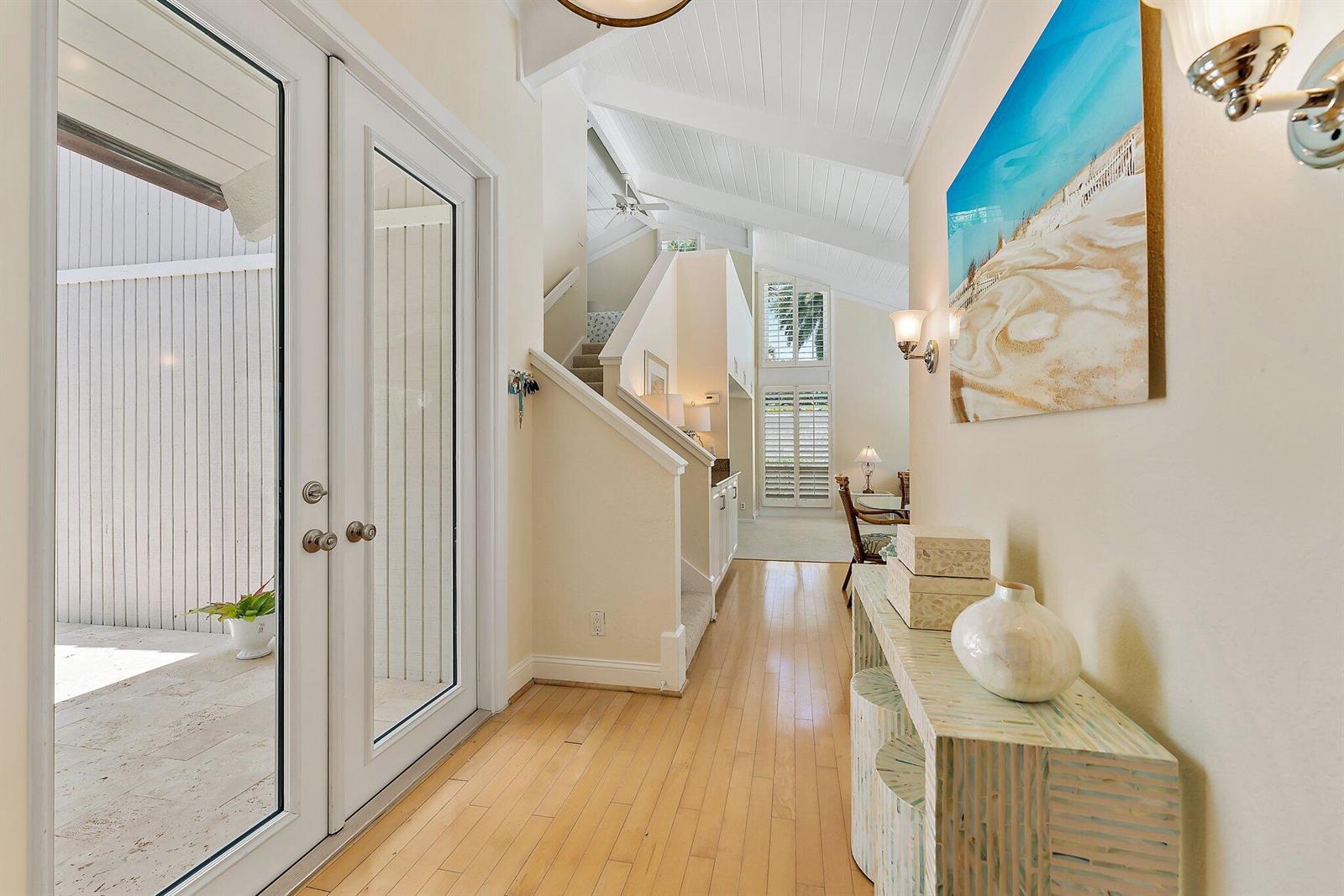 A bright entryway features hardwood floors, a staircase, and a console table with decor — 107 Mako Lane, Jupiter FL 33477, JUPITER, FL