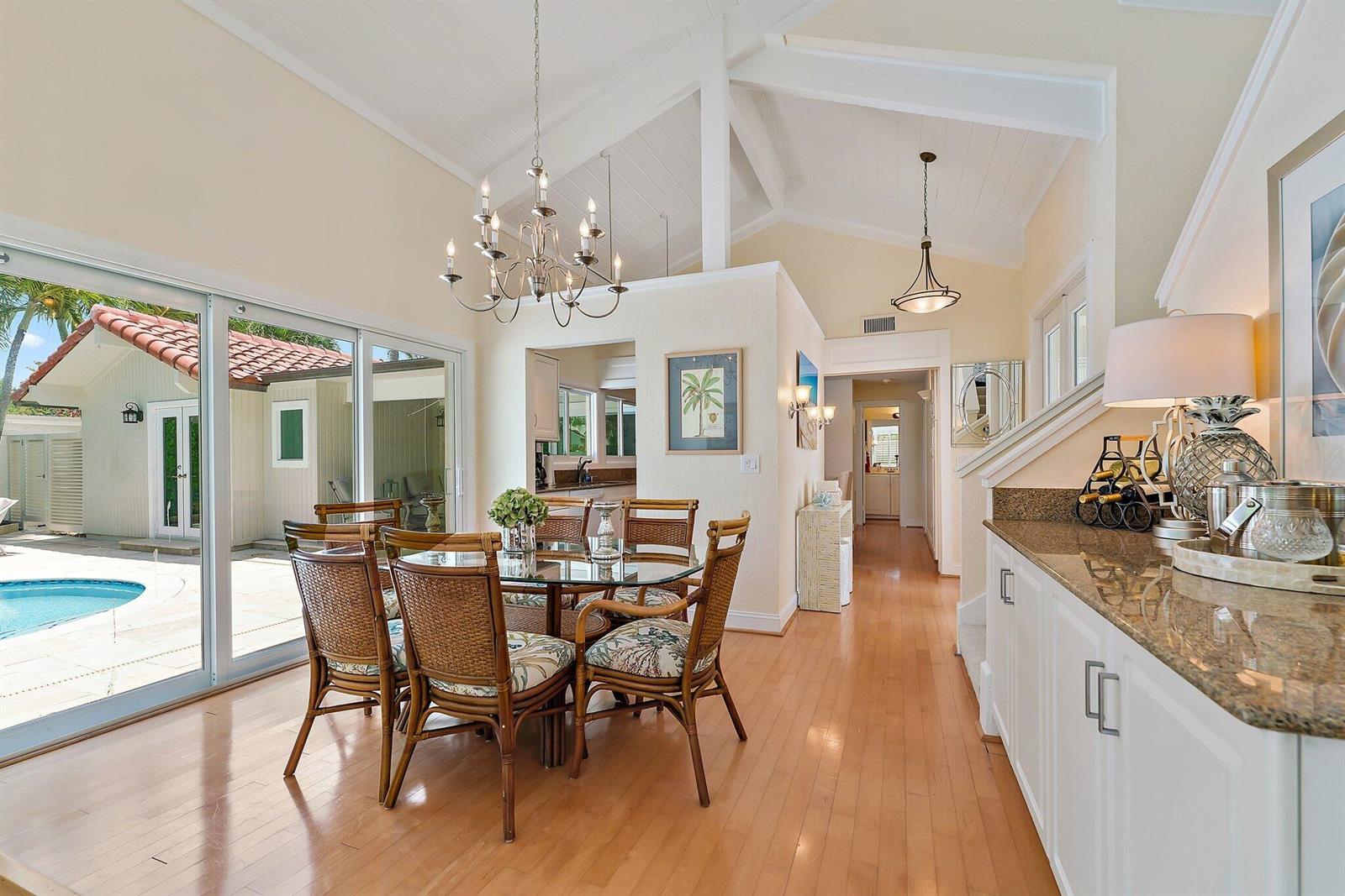 A dining room with a glass table, wicker chairs, and a view of a pool — 107 Mako Lane, Jupiter FL 33477, JUPITER, FL