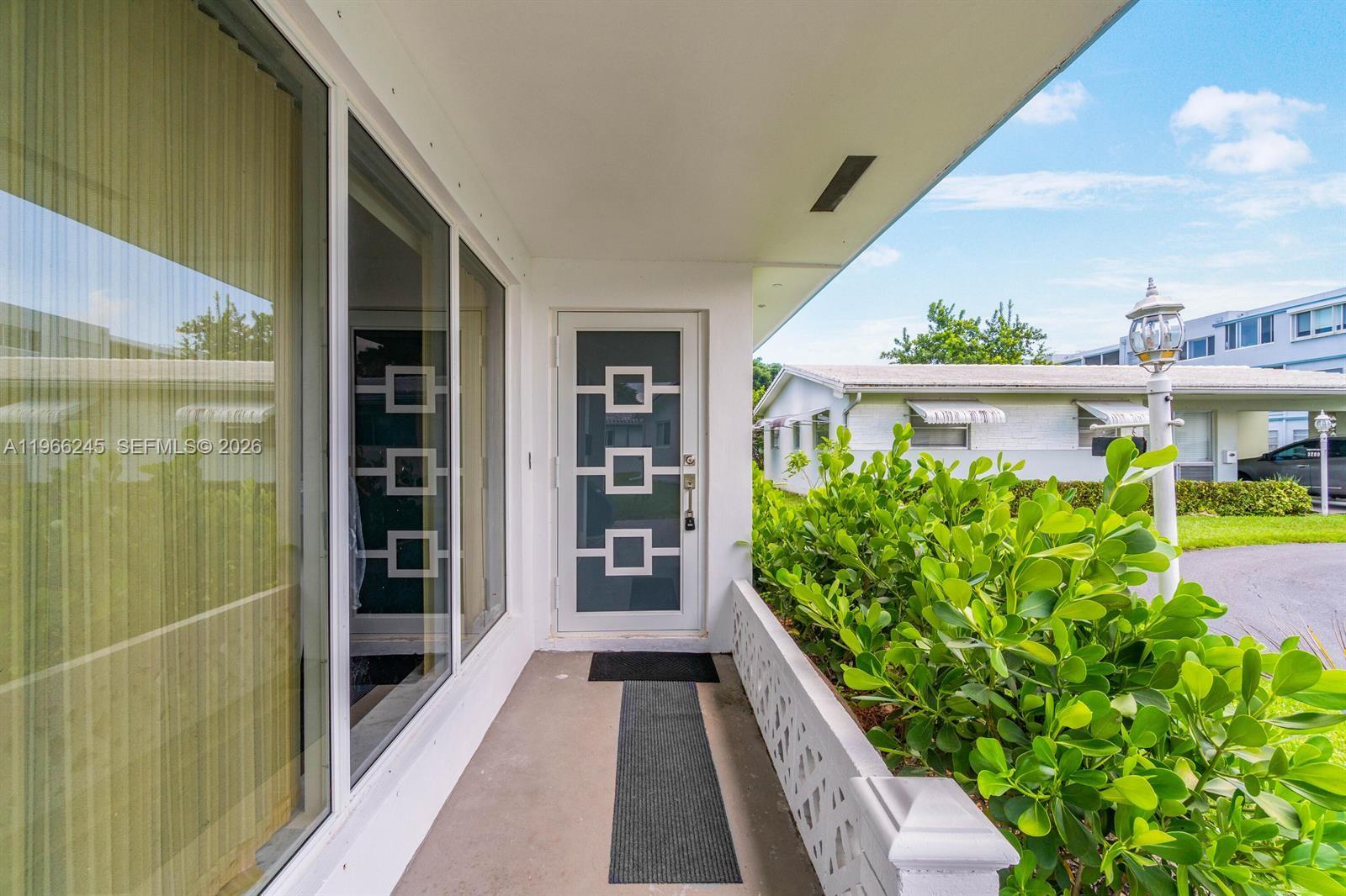 A covered porch leads to a front door with a geometric window design — 3201 Abbott Ln, Hollywood FL 33021, HOLLYWOOD, FL