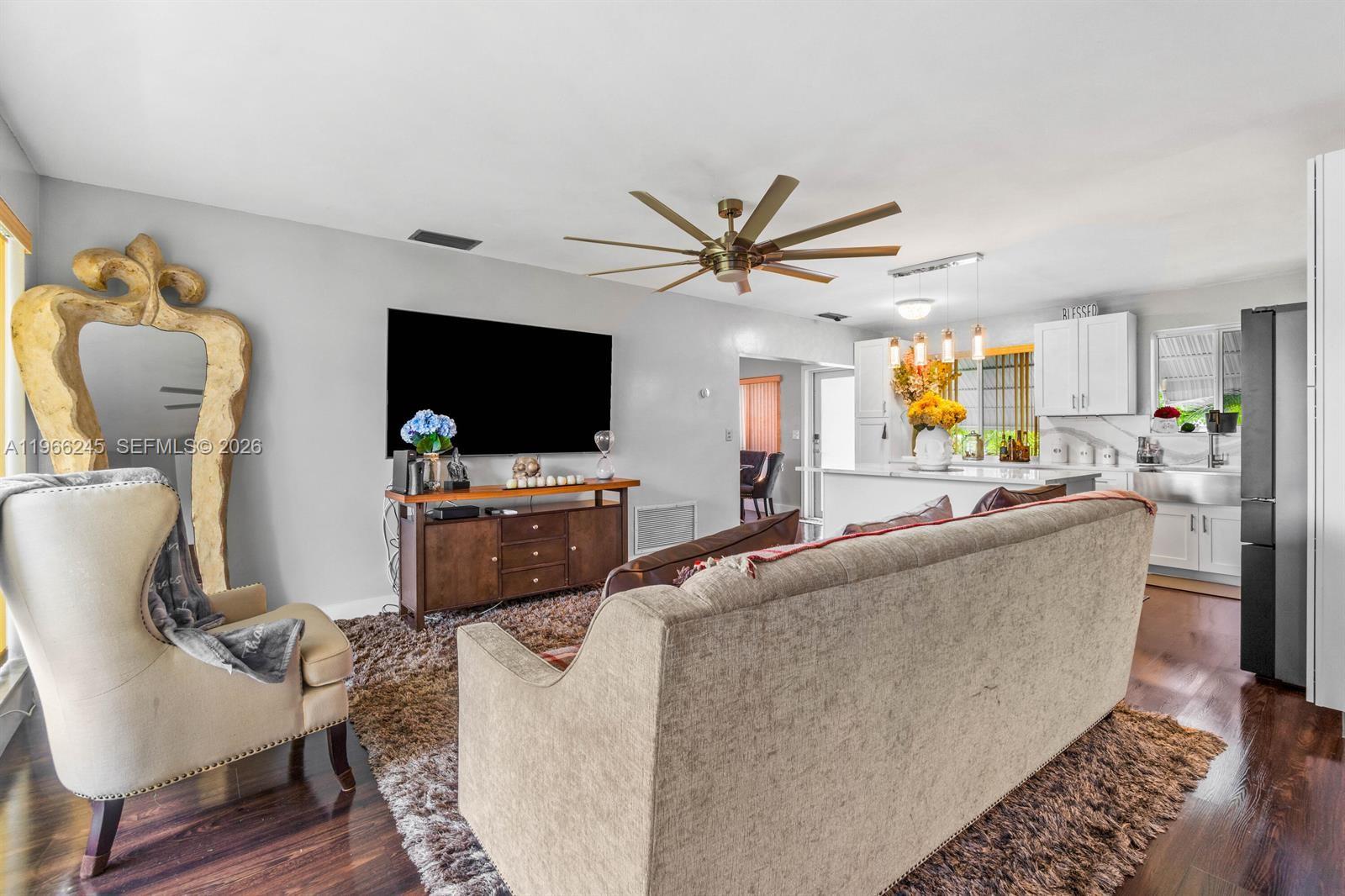 A living room with a large television, a beige sofa, and an open-concept kitchen — 3201 Abbott Ln, Hollywood FL 33021, HOLLYWOOD, FL