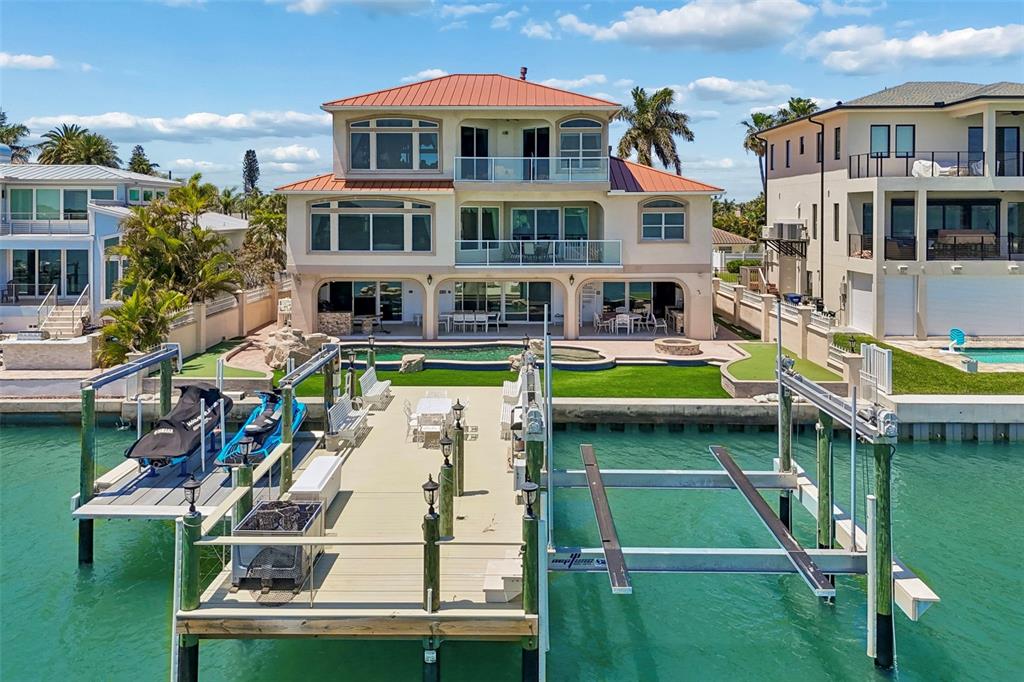 An aerial view of a three-story waterfront home with a private dock and swimming pool — 1203 BAY DRIVE, BELLEAIR BEACH, FL