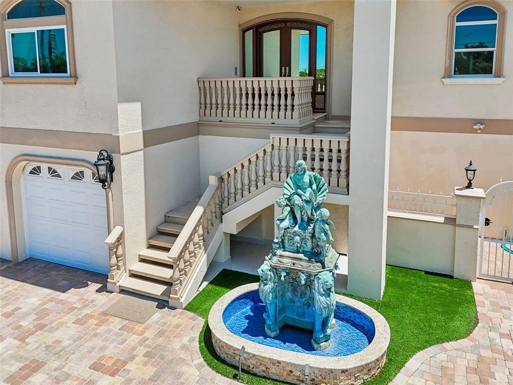 An ornate fountain sits in front of a house with a staircase leading to the entrance — 1203 BAY DRIVE, BELLEAIR BEACH, FL